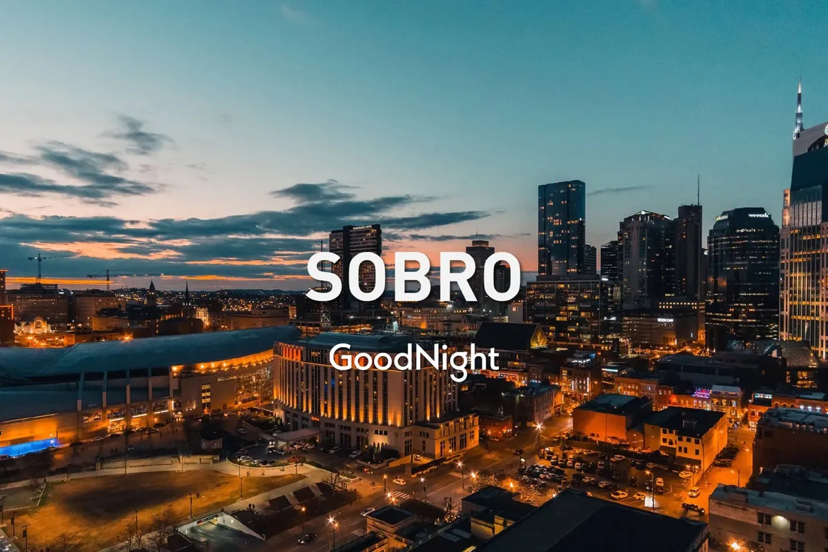 A panoramic city skyline at dusk, with illuminated buildings and a rich sunset sky. The tranquil yet vibrant scene hints at the rooftop deck experience, blending relaxation with urban excitement.