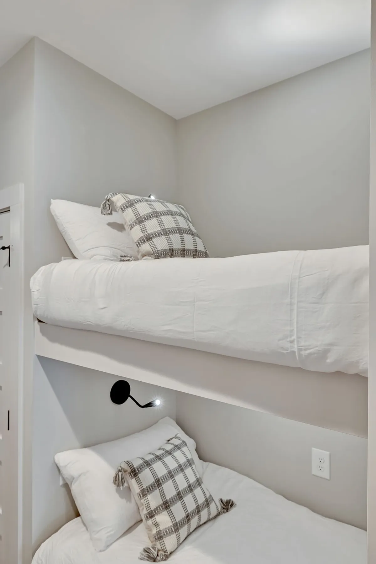 An inviting hallway bunk area with two twin beds, each equipped with decorative pillows and a personal reading light. The setup is compact and designed for comfort, making it ideal for children or extra guests, as referenced in the section.