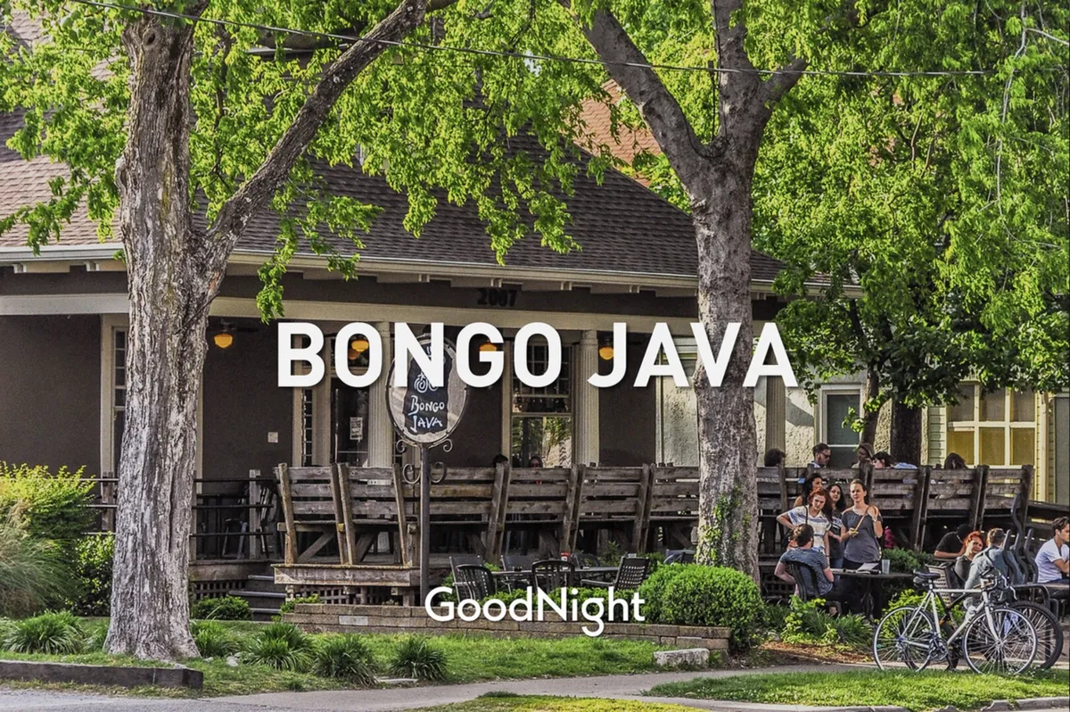 A charming exterior cafe scene with the Bongo Java sign, outdoor seating, and people socializing over coffee. The setting is relaxed and welcoming, with space for dogs and their owners to relax on the patio and watch the street life.